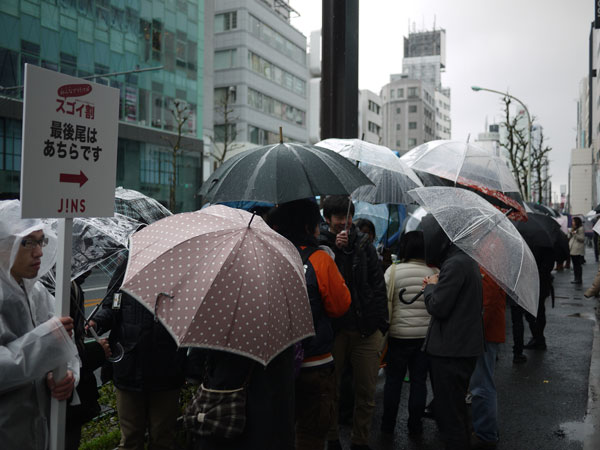 （写真1）雨が降る中、割引クーポンを求めて行列をなす人々。image by JINS