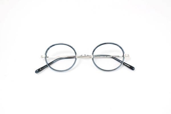 Ackermanは、顔にきれいになじむシンプルなオーバル型。Oliver Peoples（オリバーピープルズ）らしいクラシックなデザインに、「ネイビー×シルバー」のコンビネーションカラーでモダンな要素がプラスされ、現代的かつモードな印象に。